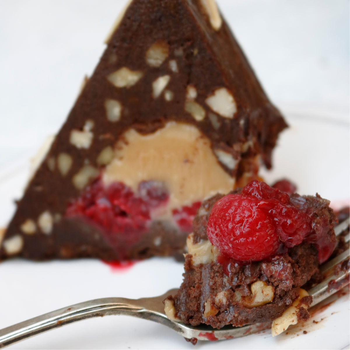 Delicioso postre de chocolate con manjar, frambuesas y almendras tostadas
