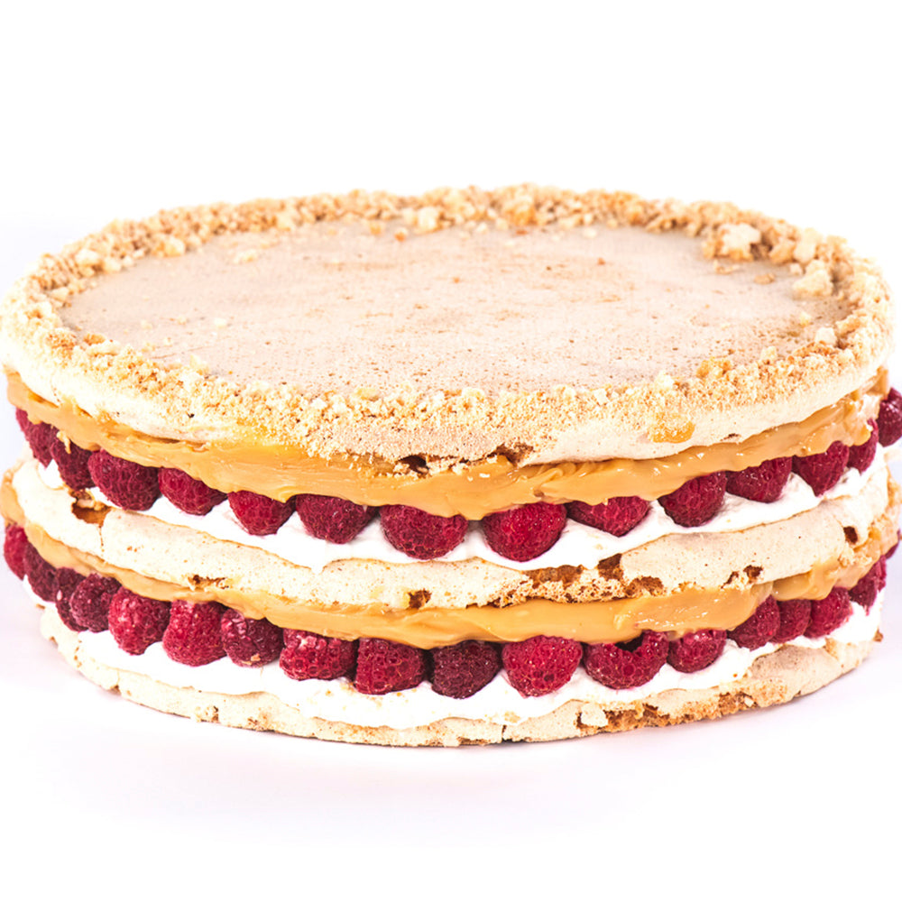Torta de merengue con almendras, rellena de manjar, crema y frambuesas enteras